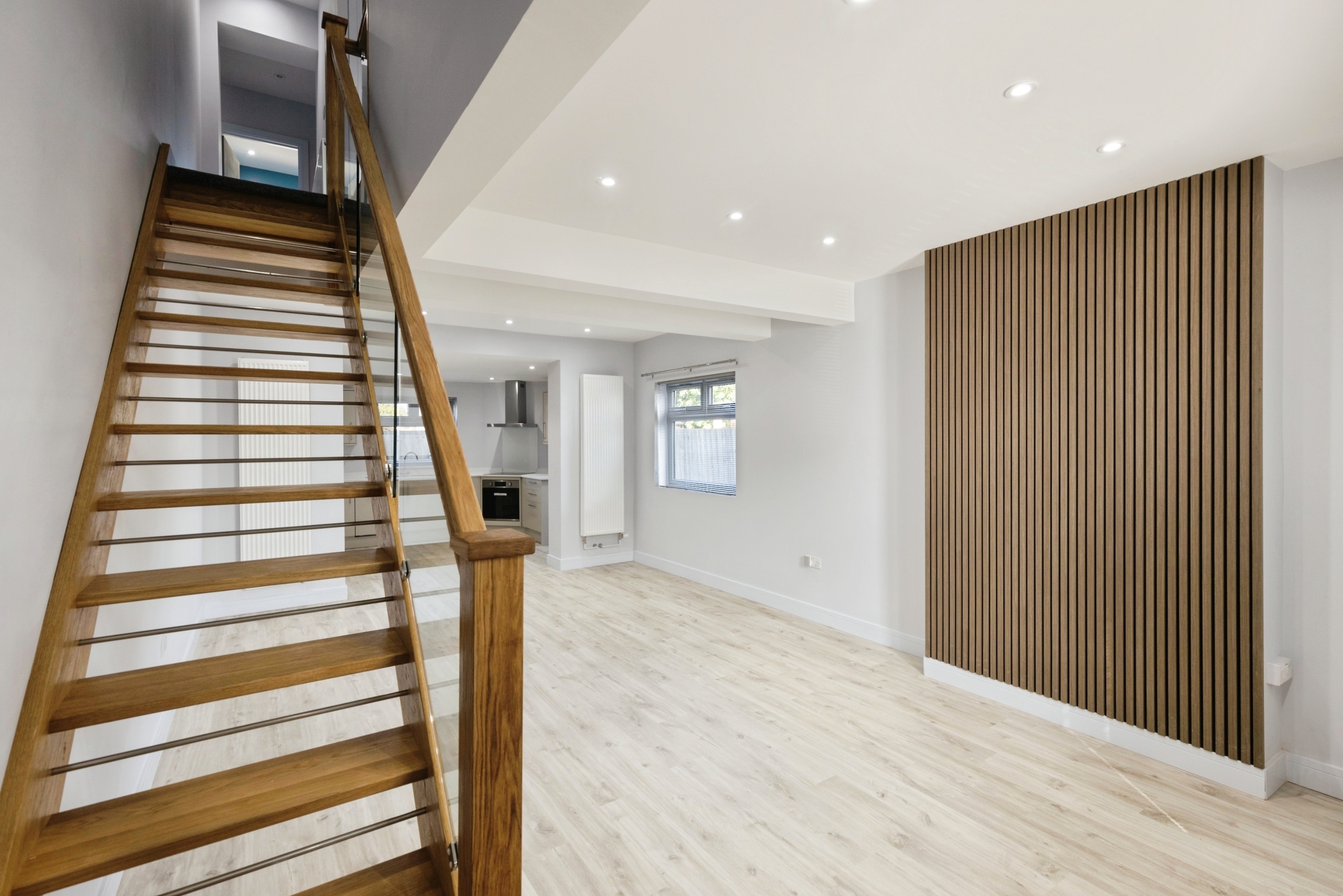 Bright renovated living space with oak staircase and timber feature wall
