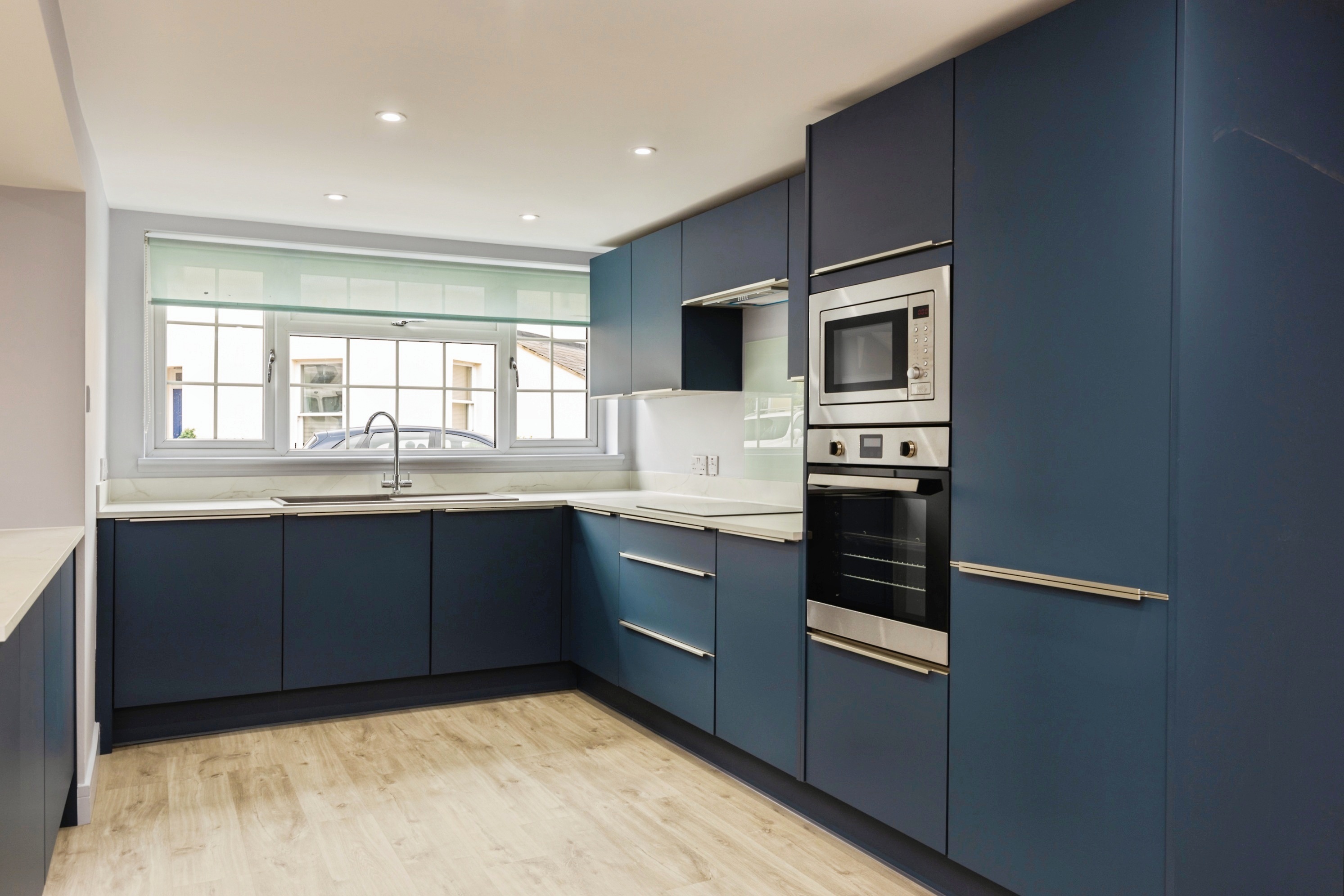 Modern fitted kitchen with deep blue cabinetry and integrated appliances